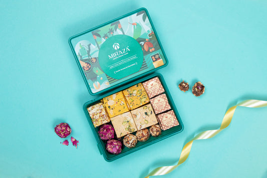 Assorted candies in a decorative tin with 'Mithaza' branding on a blue background